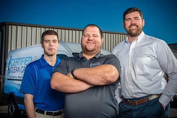 Certified Clean Care Team in front of their work trucks.